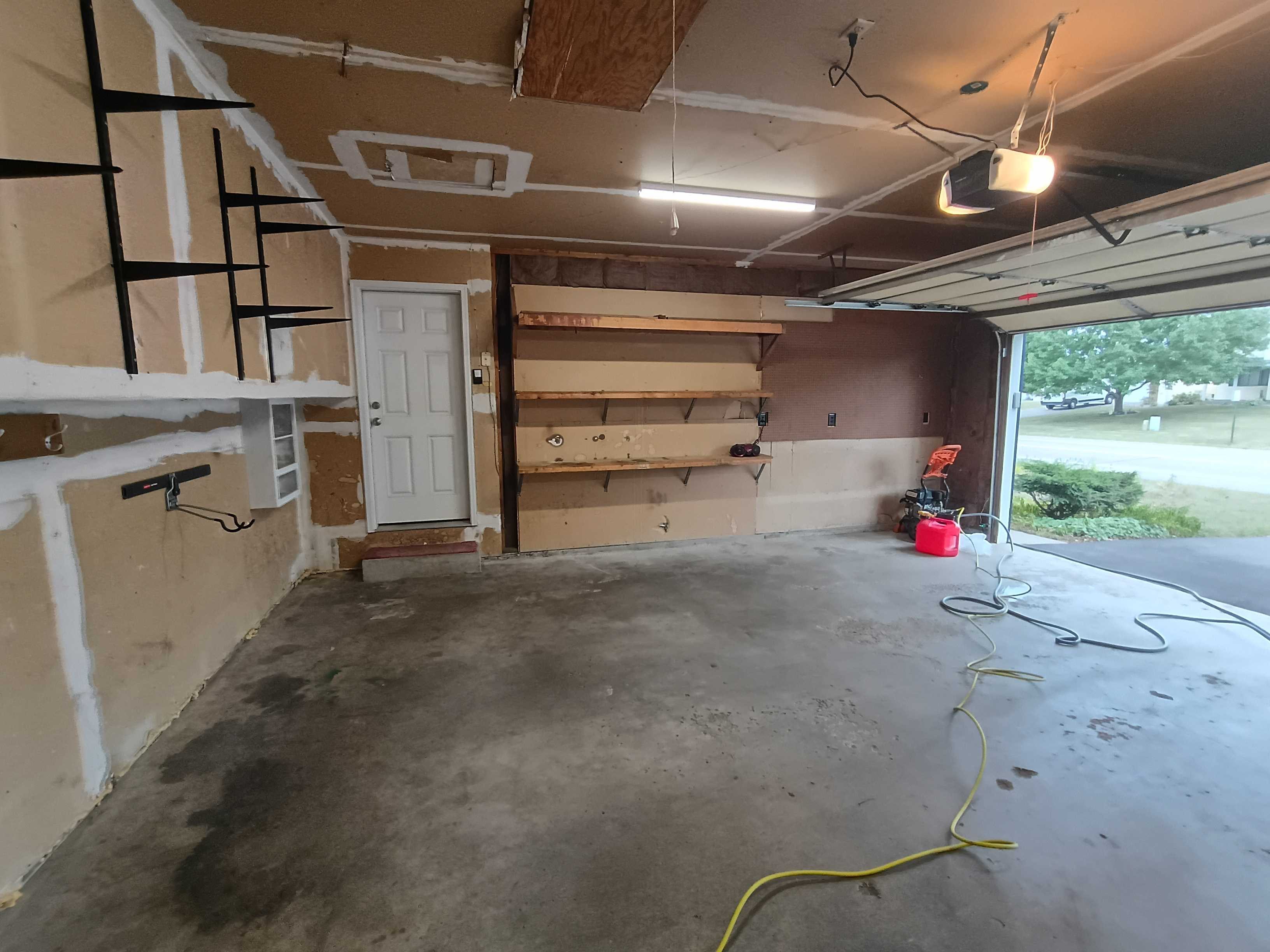 Cottage Grove garage interior before painting, bare drywall and unfinished wood shelves