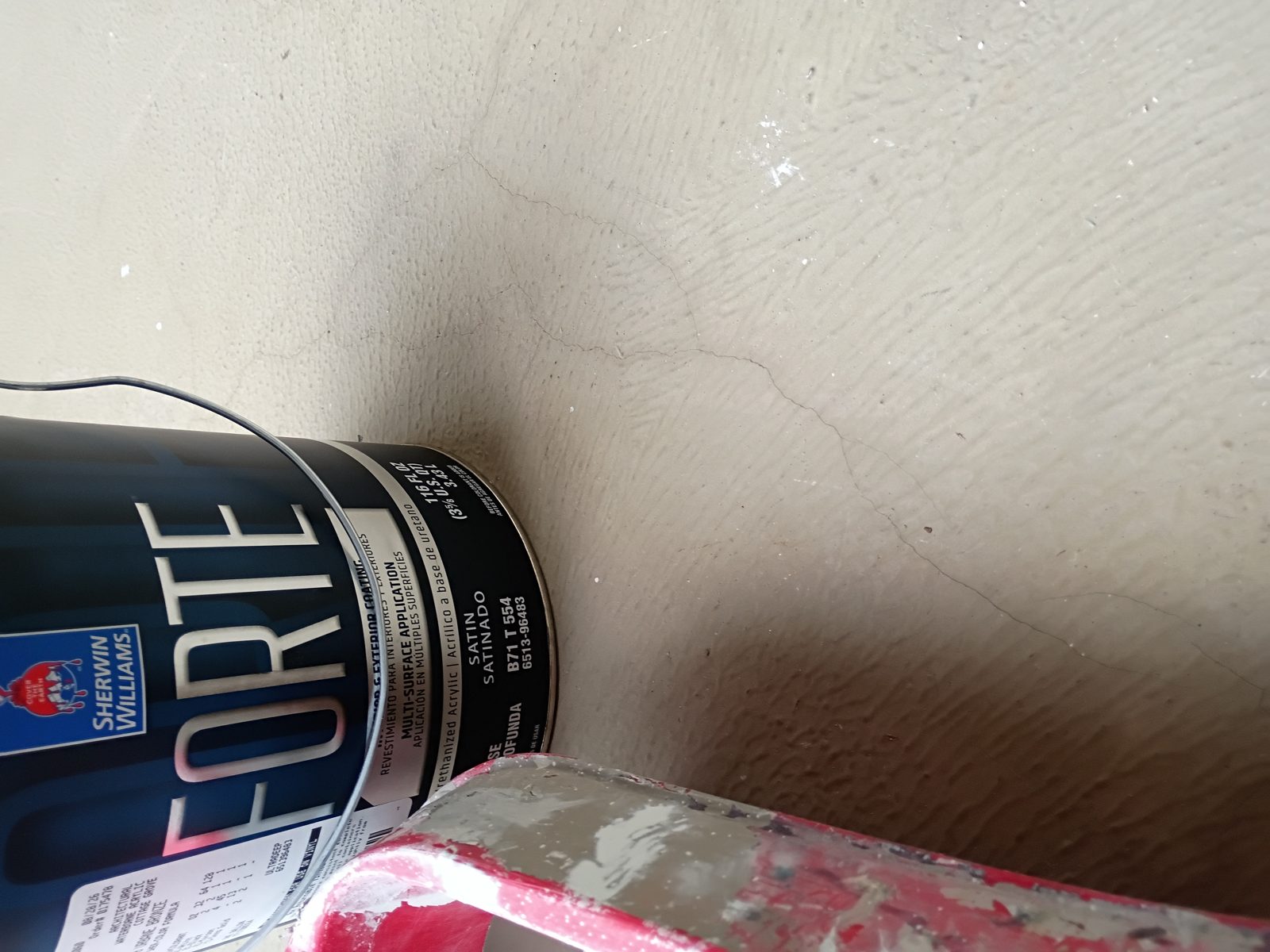Forte satin can next to cracked textured concrete on the balcony